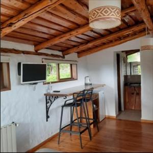 Habitación con bar con taburetes y TV en la pared en Sukal en El Bolsón