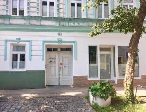 un edificio blanco con una puerta y un árbol en Danube Art Apartments, en Viena