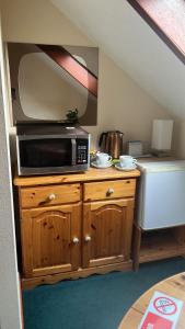 a microwave on top of a wooden cabinet with a refrigerator at An Escape for 2: Near a Castle Island in Scotland in Kinross