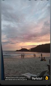 um grupo de pessoas na praia ao pôr do sol em Chalés da Jack em Angra dos Reis