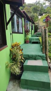 a green house with stairs and potted plants at Chalés da Jack in Angra dos Reis