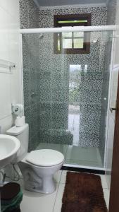 a bathroom with a toilet and a glass shower at Chalés da Jack in Angra dos Reis