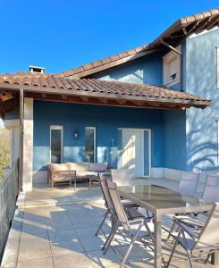 un patio con mesa y sillas frente a una casa azul en Cangas Relax En Grupo, en Cangas de Onís