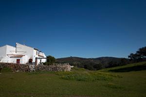 una casa blanca en una colina con una pared de piedra en Casa Cortijo en Dehesa Sierra León, en La Puebla de los Infantes