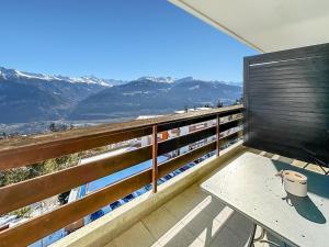 balcón con mesa y vistas a las montañas en Mon Pied à Terre à Crans-Montana en Crans-Montana