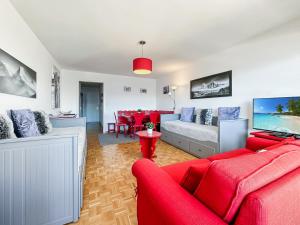 ein Wohnzimmer mit einem roten Sofa und einem TV in der Unterkunft Mon Pied à Terre à Crans-Montana in Crans-Montana