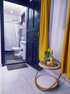 a bathroom with a yellow door and a table with flowers at Lux Suites Milimani Furnished Apartments in Kisumu