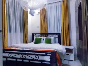 a bedroom with a bed with green pillows and curtains at Lux Suites Milimani Furnished Apartments in Kisumu