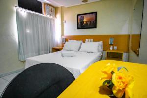 a hotel room with two beds and a yellow table at Hotel Piramide Pituba - Rua Pernambuco in Salvador