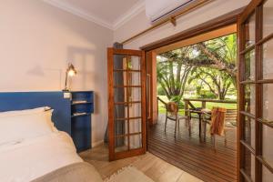 a bedroom with a bed and a balcony with a table at Sedia Riverside Hotel in Maun