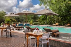 un patio con mesas y sombrillas junto a una piscina en Sedia Riverside Hotel, en Maun