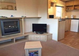 a living room with a flat screen tv and a kitchen at Tollerton Holiday Park in Huby