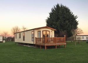 a tiny house with a porch and a deck at Tollerton Holiday Park in Huby