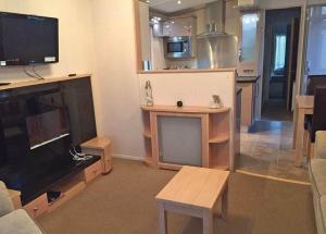 a living room with a flat screen tv and a kitchen at Tollerton Holiday Park in Huby