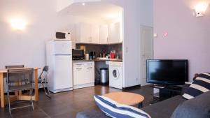 een woonkamer met een bank en een tv en een keuken bij L'île d'Olive, appartement entier 2 à 4 personnes terrasse 25 m2 Besançon, proche CV, Micropolis et CHU in Besançon