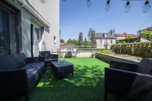 un patio con sillas y césped verde en L'île d'Olive, appartement entier 2 à 4 personnes terrasse 25 m2 Besançon, proche CV, Micropolis et CHU, en Besançon