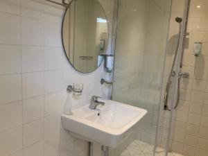 a bathroom with a sink and a shower with a mirror at Fisherman's House by Hofstad Hotels in Scheveningen
