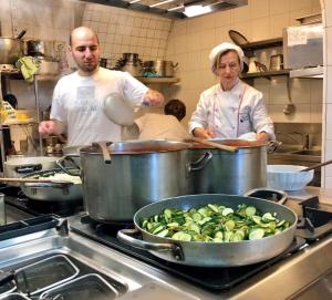 a man and a woman in a kitchen preparing food at Hotel Trattoria Pallotta in Assisi