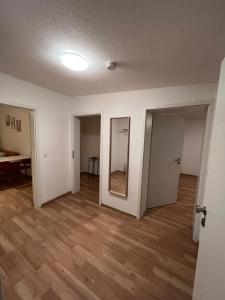 ein leeres Zimmer mit weißen Wänden und Holzböden in der Unterkunft Zentral gelegene Apartments in Gelsenkirchen für bis zu 5 Personen in Gelsenkirchen