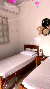 two beds in a room with pink decorations on the ceiling at BOA SORTE SUITES com PISCINA, GARAGEM GRATIS e Pé na PRAIA de GERIBÁ in Búzios