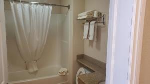 a bathroom with a shower with a white shower curtain at Shoreside Inn & Suites in Wabamun