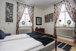 ein Schlafzimmer mit einem Bett und zwei Fenstern in der Unterkunft HagbackensGård Bed&Breakfast in Örebro