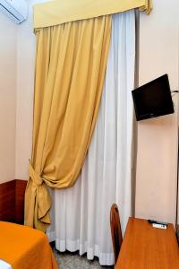 ein Schlafzimmer mit einem gelben Vorhang und einem TV in der Unterkunft Hotel Cervia in Rom