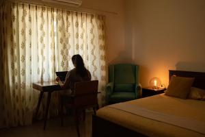 una mujer sentada en un escritorio en una habitación de hotel con un ordenador portátil en Luho 206, en Bangalore
