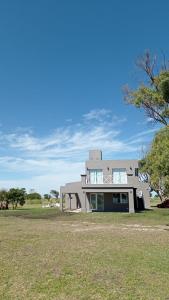 a house on a grass field with a blue sky at COMPLEJO LA ISLA MAR CHIQUITA in Balneario Mar Chiquita