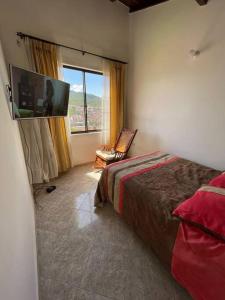 1 dormitorio con 1 cama, TV y silla en Apto. en zona céntrica con vista panorámica al pueblo en San Gil