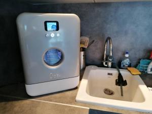 a kitchen with a washing machine next to a sink at L'île d'Olive, appartement entier 2 à 4 personnes terrasse 25 m2 Besançon, proche CV, Micropolis et CHU in Besançon +15 photos