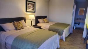 a hotel room with two beds and a lamp at Shoreside Inn & Suites in Wabamun