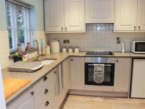 a kitchen with white cabinets and a stove top oven at Divine, detached countryside cottage near Ludlow. in Ludlow