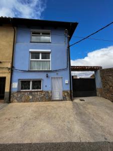 a blue house with a driveway in front of it at Casa Rural Maroto in Campillo