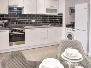 a kitchen with white cabinets and a table and chairs at The Farmhouse - Uk42780 in Hemsby