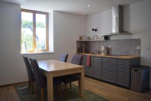 a kitchen with a table and some chairs and a counter at Spacious apartment in old farm close to Lac de Vouglans in La Tour-du-Meix