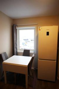 a kitchen with a table and a refrigerator and a window at Sentral leilighet med 3 soverom 2etg in Harstad