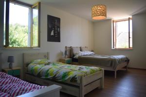 a bedroom with two beds and two windows at Spacious apartment in old farm close to Lac de Vouglans in La Tour-du-Meix