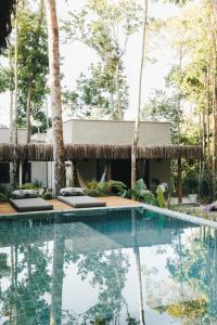 un complejo con piscina y palmeras en CASA SUKHA Hotel en Trancoso