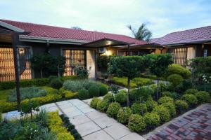 a garden in front of a house with bushes and trees at Avalon Guest Manor in Newcastle