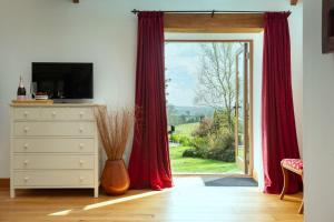 a room with a sliding glass door with red curtains at Linhay at East Trenean Farm -Luxury retreat for 2 with stunning rural views, private hot tub and EV charging in Looe