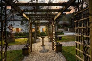 a wooden pergola with a table in a garden at Linhay at East Trenean Farm -Luxury retreat for 2 with stunning rural views, private hot tub and EV charging in Looe +14 photos