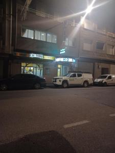 dos autos estacionados frente a una gasolinera por la noche en Hotel 2 de mayo 2, en Xinzo de Limia