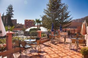 un patio con mesas, sillas y sombrillas en Hotel Saint Antoine, en Tafraoute