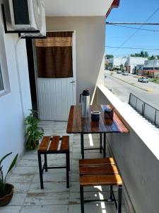 einen Tisch und Bänke auf dem Balkon eines Gebäudes in der Unterkunft Complejo Las Palmeras in Tandil