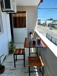 una mesa y bancos en el balcón de un edificio en Complejo Las Palmeras en Tandil