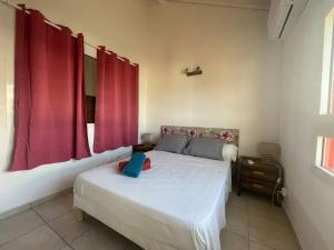una camera da letto con un letto bianco con tende rosse di Horizon bleu Caraibes a Le Moule
