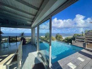 a house with a swimming pool and a view of the ocean at Horizon bleu Caraibes in Le Moule