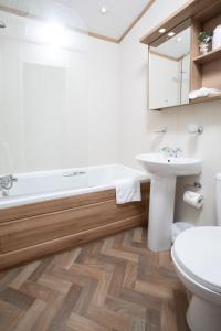 a bathroom with a tub and a sink and a toilet at Stewart Resort Lodge 25 in St Andrews