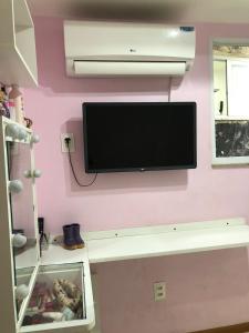 a flat screen tv hanging on a pink wall at Cobertura com Piscina na Lapa in Rio de Janeiro